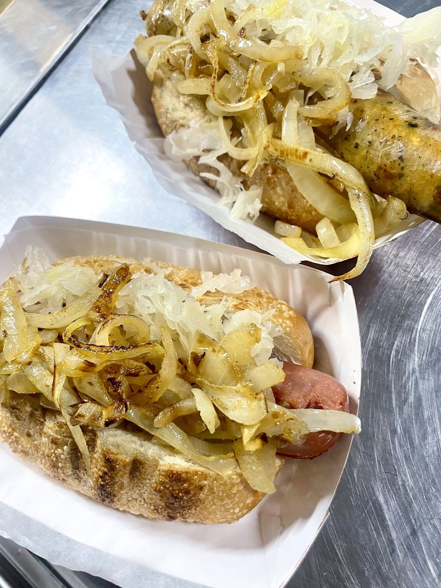 Two sausages on rolls piled high with grilled onions and sauerkraut